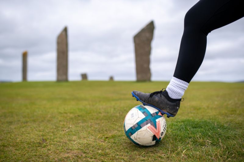 A person's foot on a football, in Orkney.