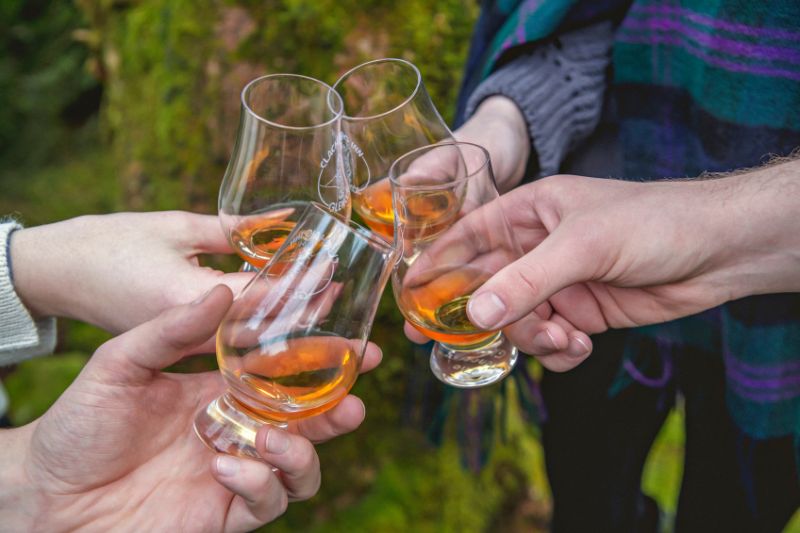 Group of people clinking whisky glasses