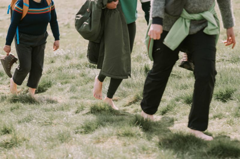Three woman walking barefoot outdoors in Scotland with company WanderWomen